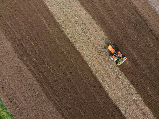 Aerial view of an agricultural field with a farmer working on a tractor.