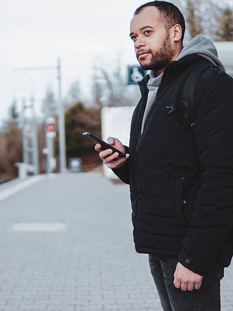 istock Traveler checking mobile phone at Train Station Platform. Man using smartphone while waiting for Train 2211407911