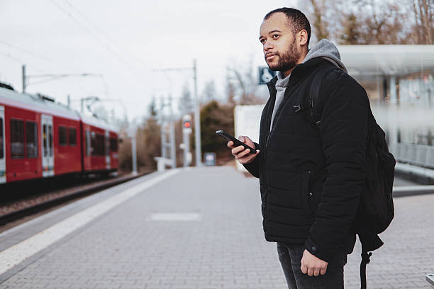 istock Traveler checking mobile phone at Train Station Platform. Man using smartphone while waiting for Train 2211407913