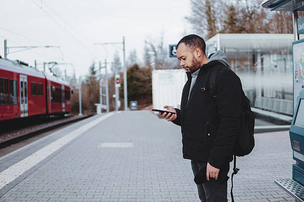 istock Traveler checking mobile phone at Train Station Platform. Man using smartphone while waiting for Train 2211407916