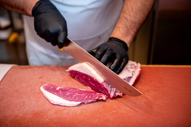 istock Butcher cutting picanha with large knife on meat cutting board 2211408406