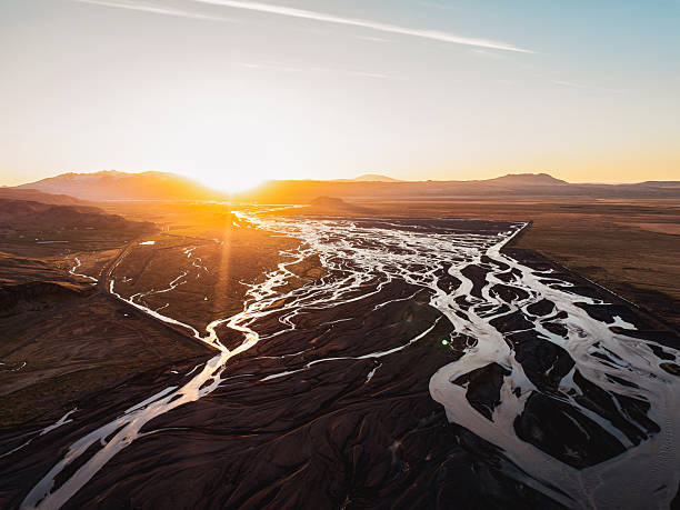 Sunset over braided glacial river flowing through a vast volcanic plain in Iceland.