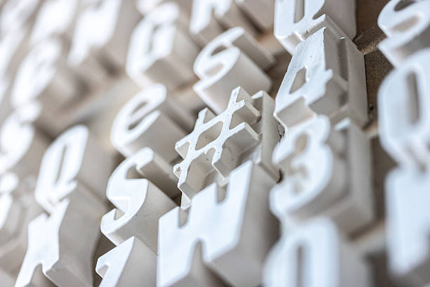 Abstract close-up view of three-dimensional white alphabetical characters arranged decoratively on a surface, with a soft focus creating depth and texture. Ideal for creative concepts and modern designs.