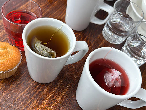 Stock photo captures the soothing ritual of making fruit teas using teabags, set against a serene tea break scene. White china mugs and clear water glasses are neatly arranged, emphasizing simplicity and refreshment