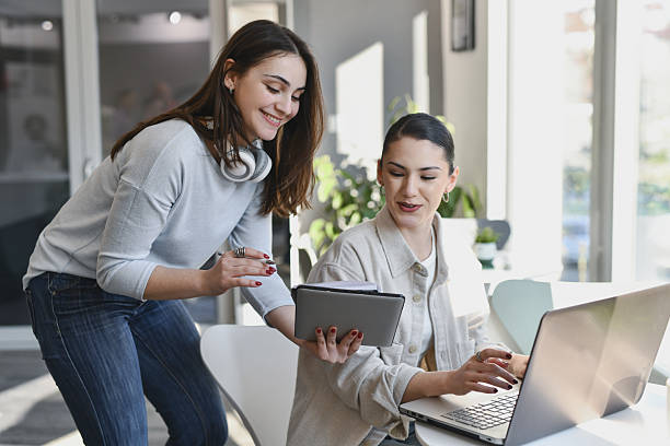 istock Joyful Female Coworkers Cooperating on Project Discussing Notes on Tablet 2211421533