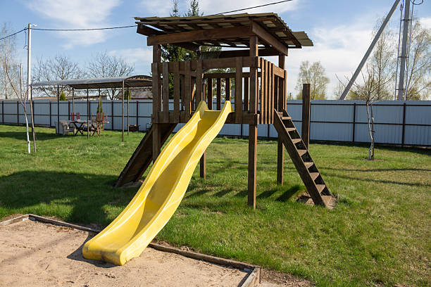 istock A wooden play structure and swing-set is centered on a grassy lawn 2211421612