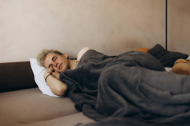 istock Young Man Resting Peacefully on a Comfortable Bed With a Grey Blanket 2211422602