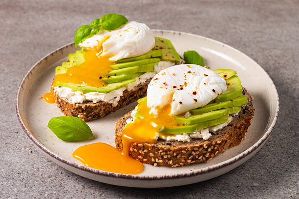istock Toast with avocado, soft cream cheese, rye bread and poached Egg. Wholemeal open sandwich for healthy breakfast concept 2211426852
