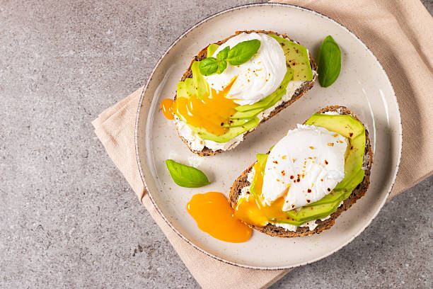istock Toast with avocado, soft cream cheese, rye bread and poached Egg. Wholemeal open sandwich for healthy breakfast concept 2211426997