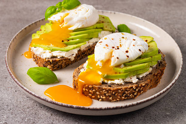 istock Toast with avocado, soft cream cheese, rye bread and poached Egg. Wholemeal open sandwich for healthy breakfast concept 2211427008