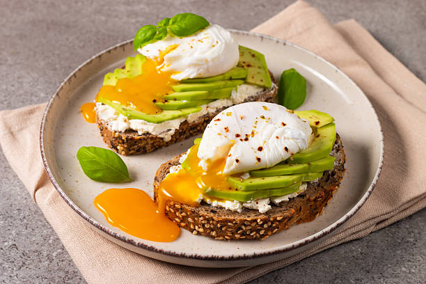 istock Toast with avocado, soft cream cheese, rye bread and poached Egg. Wholemeal open sandwich for healthy breakfast concept 2211427070