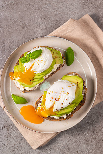 istock Toast with avocado, soft cream cheese, rye bread and poached Egg. Wholemeal open sandwich for healthy breakfast concept 2211427072