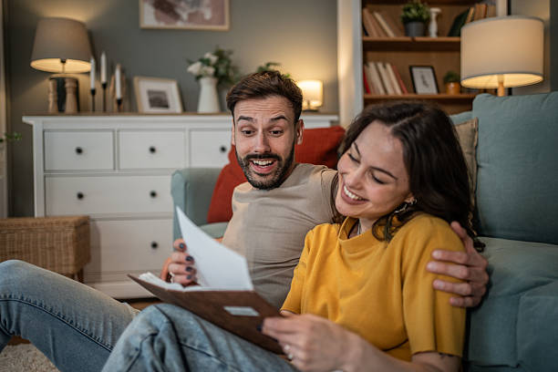istock Happy couple reading a letter at home 2211429471