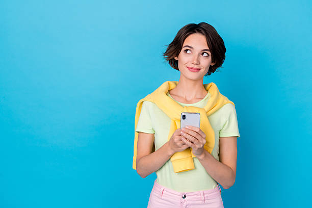 istock Photo of dreamy adorable lady dressed yellow pullover looking empty space holding modern gadget isolated blue color background 2211437764