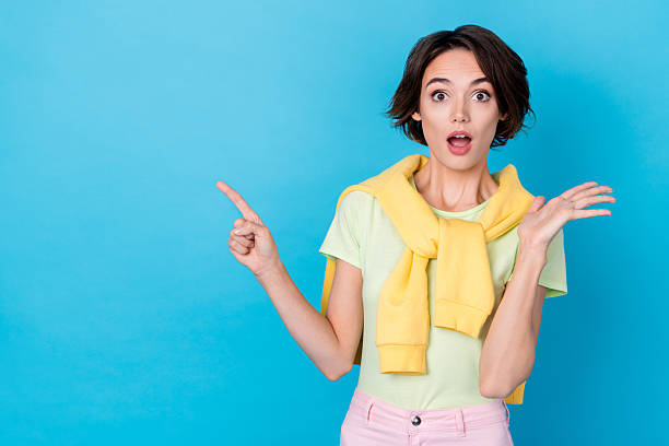istock Photo of cute excited lady dressed yellow pullover pointing two fingers empty space isolated blue color background 2211439614