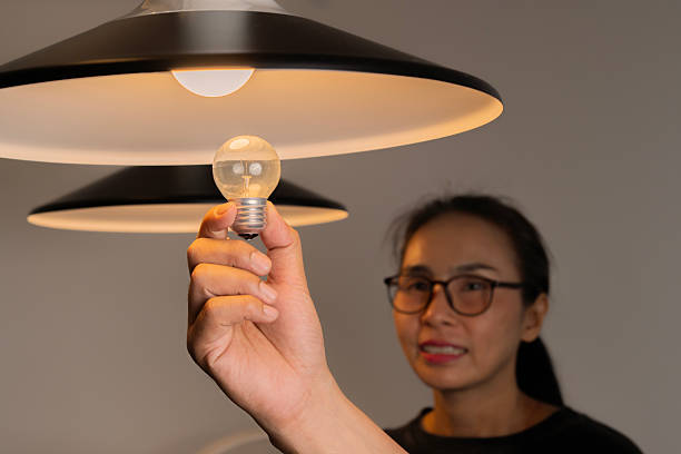 istock Selective focus of handsome man hand changing light bulb near attractive girlfriend. 2211442643