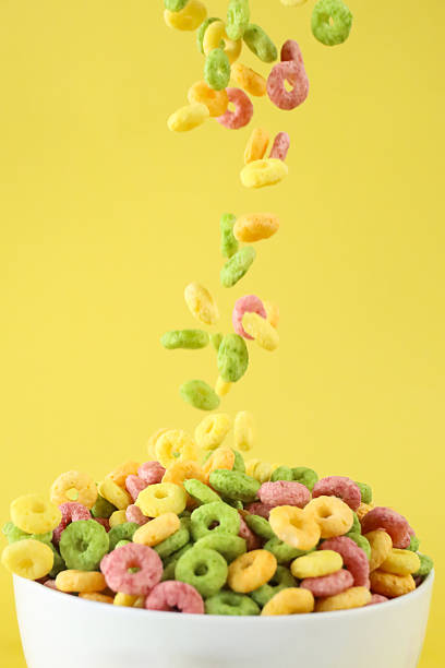 istock Image of rainbow fruity fruit loops falling into bowl / colorful cereal hoops and coloured rings, fun and vibrant breakfast concept 2211444103