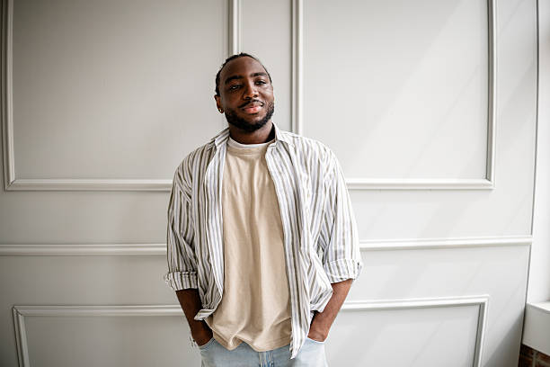 istock Young black man exudes confidence and style while smiling against a contemporary indoor backdrop 2211444819