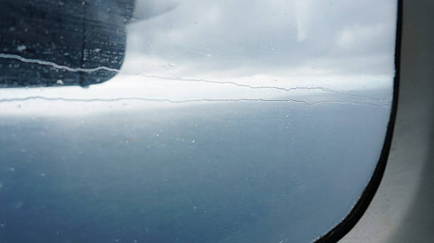 istock Scratched airplane window showing ocean and clouds 2211445783