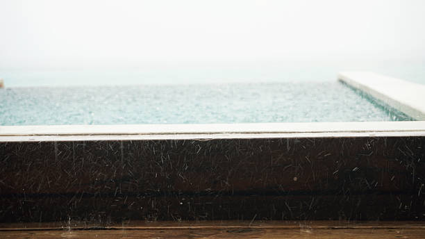 istock Rain falling on infinity pool by the ocean during a stormy day 2211446527