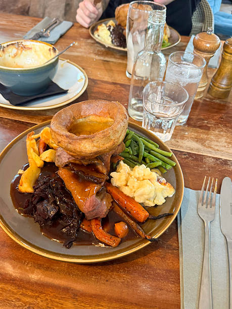 istock Image of classic sunday roast beef dinner with yorkshire pudding, gravy, carrots, vegetables / hearty traditional lunch plate, family gatherings 2211447068