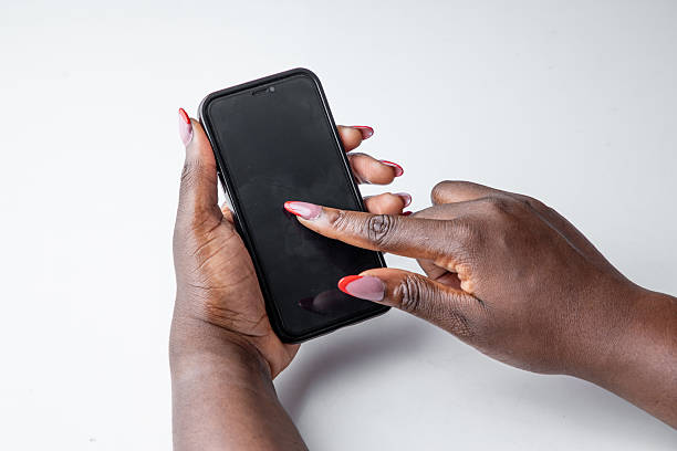 Close-up of a dark-skinned woman’s hands interacting with a smartphone, isolated on a white background
