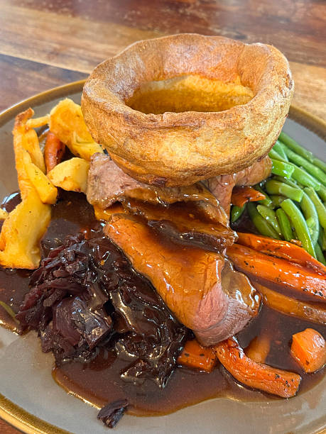 istock Image of traditional sunday roast beef dinner with purple cabbage, yorkshire pudding, gravy, carrots, vegetables / classic British comfort food 2211447491
