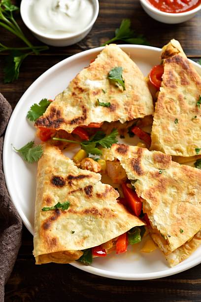 istock Chicken quesadilla with fresh vegetables on wooden table 2211447548