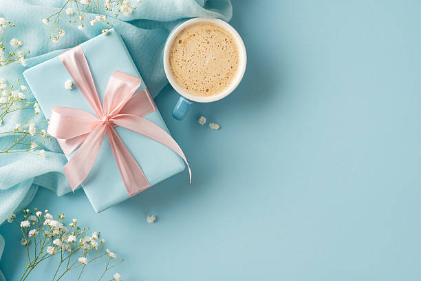 istock Present beautifully wrapped in blue paper with pink ribbon, placed beside a coffee cup 2211449185