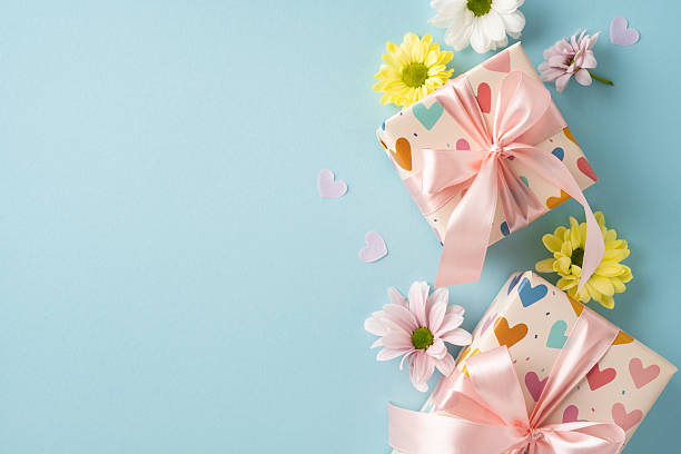 istock Two wrapped gift boxes with heart designs and pink bows, surrounded by colorful flowers 2211449200