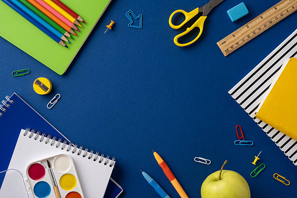 istock Assorted educational supplies including pencils, notebooks, and stationery placed on a blue surface 2211449218