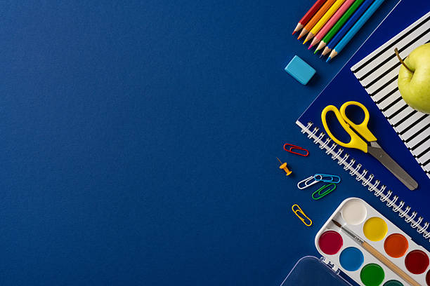 istock Various colorful school supplies including pencils, scissors, and a notebook placed neatly on a blue background 2211449224