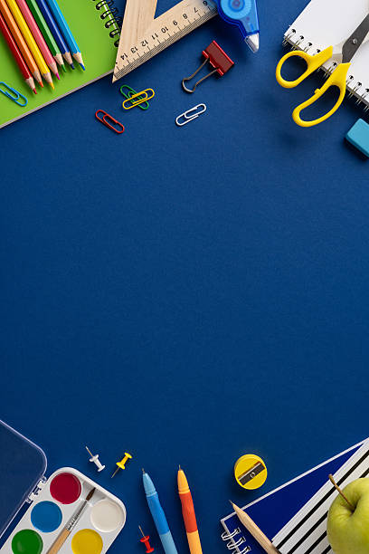 School vertical essentials including pencils, notebooks, scissors, and paint neatly arranged on blue paper