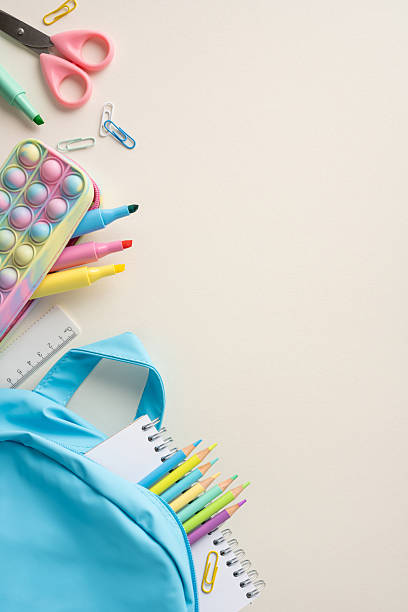 istock Back to school vertical concept with blue backpack filled with colorful supplies placed on a desk 2211449267