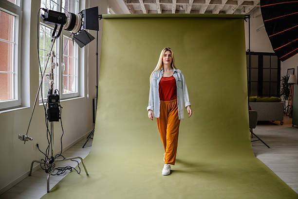 istock Young blonde woman posing confidently in a studio with modern lighting and a green backdrop while showcasing fashion and individuality 2211449382