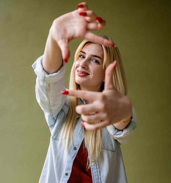 istock Young blonde woman poses confidently with playful gestures in a modern studio setting 2211449795