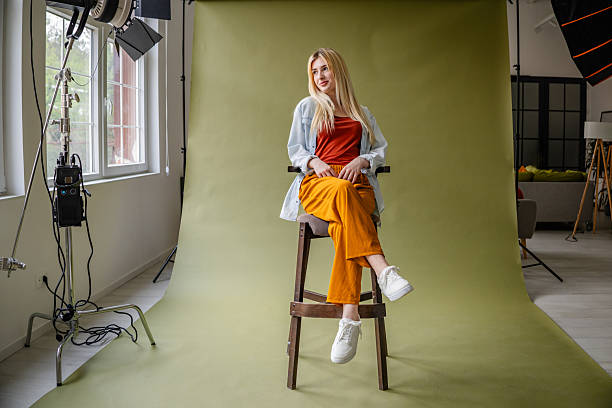 istock Young blonde woman poses confidently in a vibrant studio setting with modern lighting and colorful backdrop 2211450763