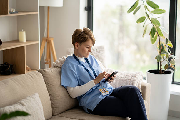 istock Nurse Relaxing on Couch While Using Smartphone in Living Room 2211450858