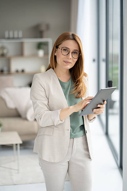 istock Smiling woman using tablet beside large window view 2211450862