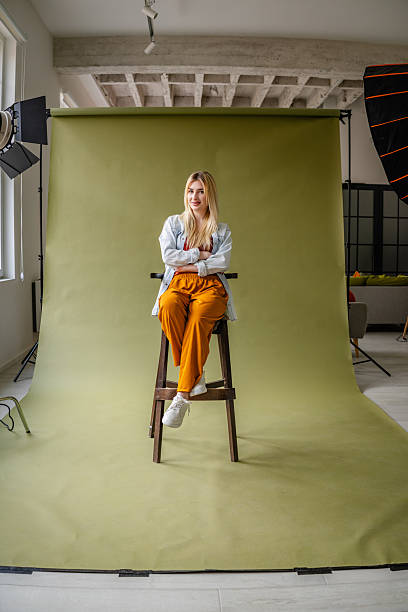 istock Young blonde woman poses confidently in a stylish studio setting with modern lighting equipment 2211451098
