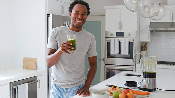 istock Portrait Of Man Wearing Pyjamas In Kitchen Drinking Freshly Made Fruit And Vegetable Smoothie 2211451749