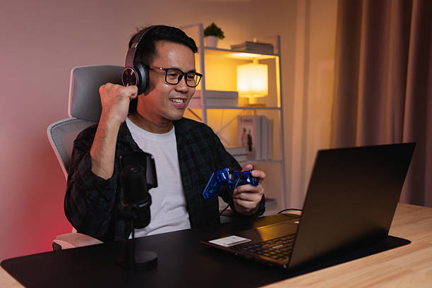 Excited Gamer Celebrating a Win While Playing Video Games at Home in a Modern Setup with Headphones and Controller in the Evening