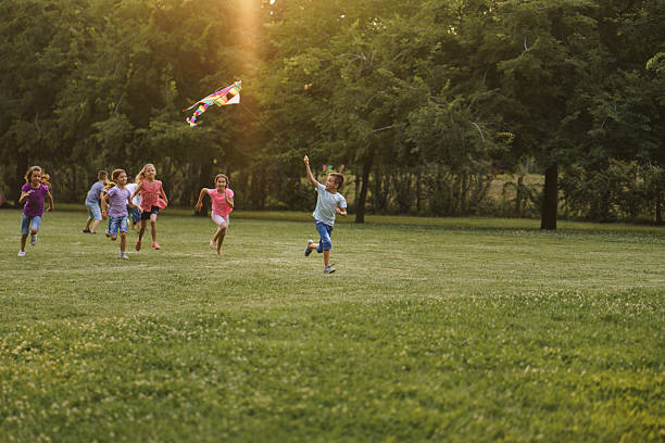istock Children run with a kite during summer day in the park 2211456224