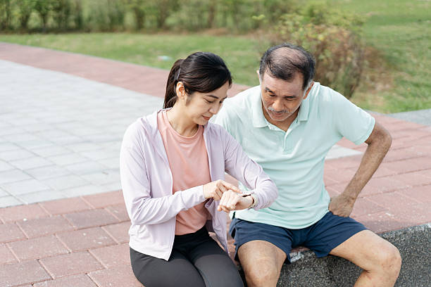 Asian family looking at smart watch while taking a break sitting on the bench