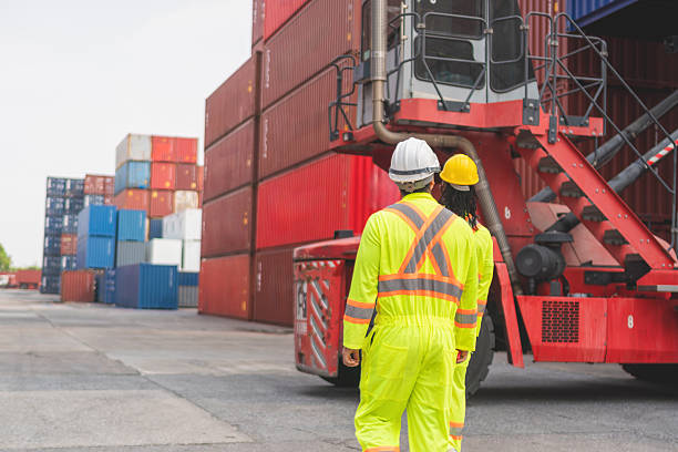 istock Back view of Engineer man Team in Safety Gear Control Containers Box at Container Cargo, Container Yard Workers Team Discussion at Shipping Yard 2211457039