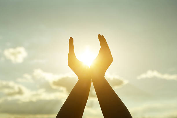 istock Hands reaching towards the sun at sunset 2211461019