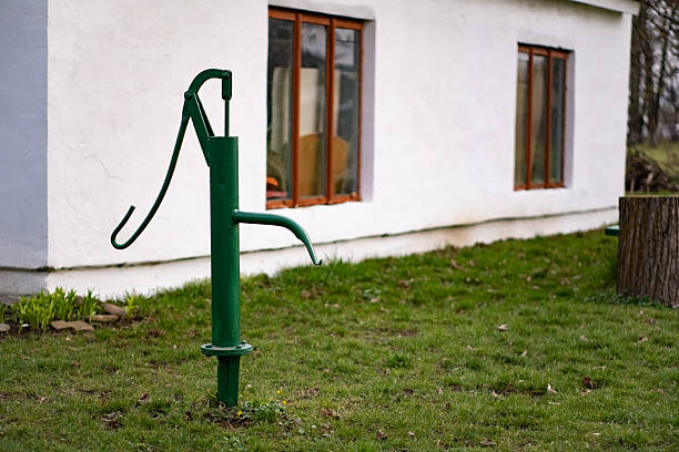 Teenager Boy Trying to Drink water on an Manual Hand Pump Near Green Field in Rural India.