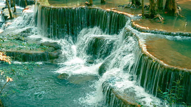 Scenic view of multi-tiered waterfall cascading over rock formations in lush green forest with flowing water creating serene and natural landscape