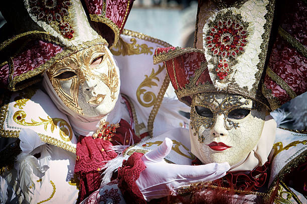 Venice, VE, Italy - February 13, 2024: Masked man wearing an original costume made of fine fabric and mirrors reflecting light at the Venice Carnival in Italy