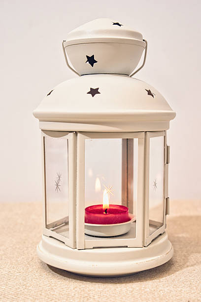 white portable lamp for wax or paraffin inserts, closed, glazed with cut-out holes casting star shadows
